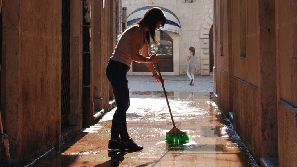 woman cleans sandstone paving slabs